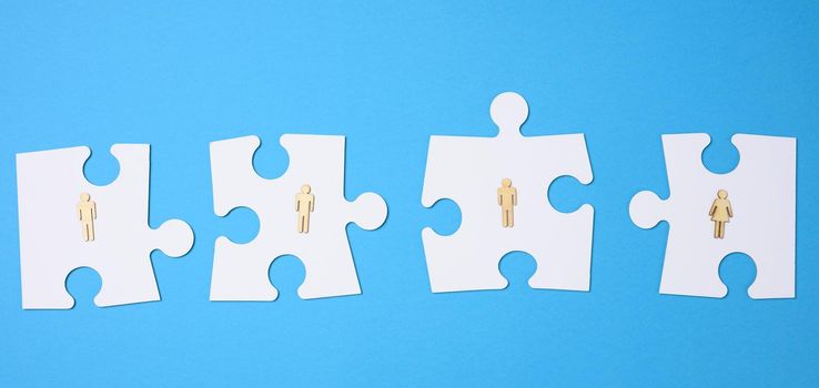 white puzzles and wooden men on a blue background. Personnel selection concept, team compatibility, individuality of each employee. Teamwork