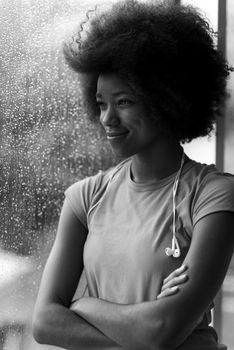 portrait of young afro american woman in gym on workout break while listening music on earphone  and dancing  rainy day and bad weather outdooor