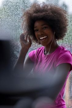 portrait of young afro american woman in gym on work out break while teaking breath and fresh water rainy day and bad weather outdooor