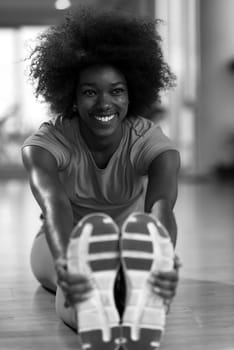 happy young african american woman in a gym stretching and warming up before workout