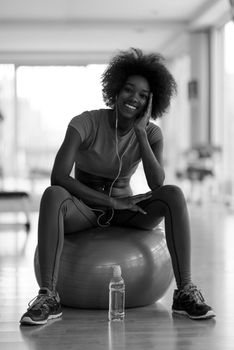 happy african american woman with a curly afro hairstyle in a  gym relaxing after pilates workout