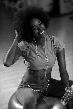 happy african american woman with a curly afro hairstyle in a  gym relaxing after pilates workout