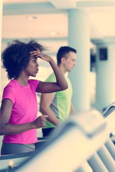 young people exercisinng a cardio on treadmill running chine in modern gym