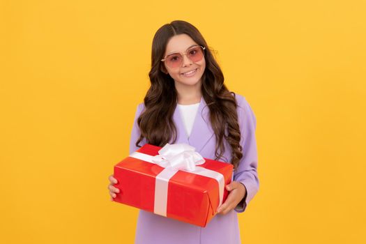 concept of shopping. sale and discount. surprise for her. boxing day. happy kid with present box. teen girl giving birthday gift. child in sunglasses and trendy suit sharing box.