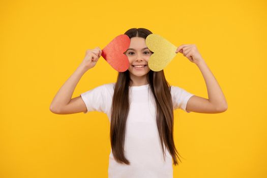 cheerful teen girl holding valentines heart on yellow background, sweetheart.