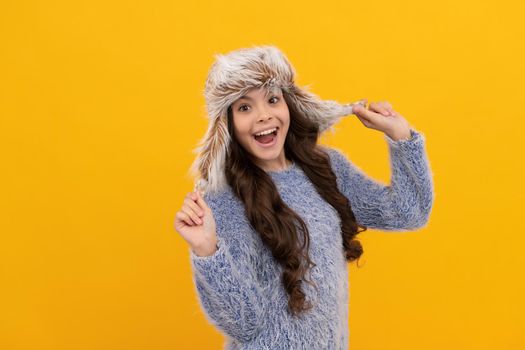 amazed teen girl wear earflap hat on yellow background, keep warm.