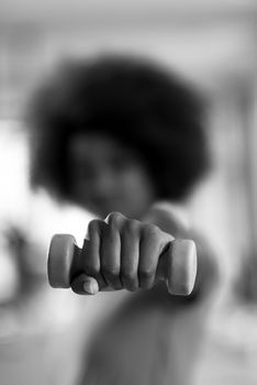 happy healthy african american woman working out in a crossfit gym on weight loss with dumbbells