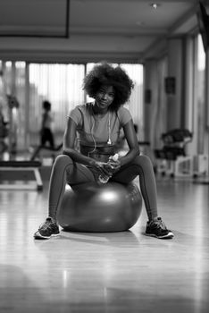 happy african american woman with a curly afro hairstyle in a  gym relaxing after pilates workout