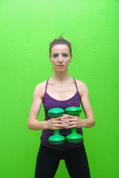 Pretty girl with dumbbells and green backgound                 