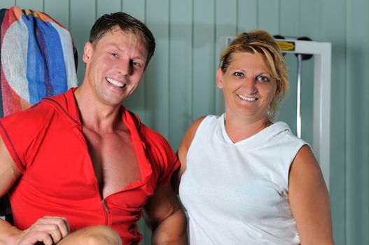 Mature woman smiling with fitness trainer in gym 
