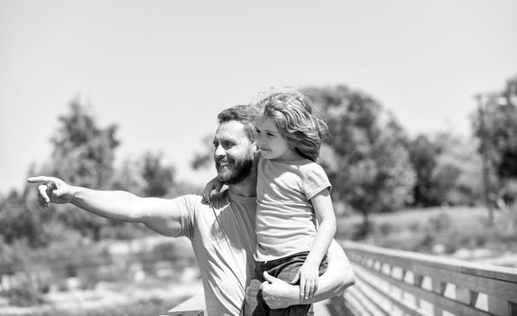 Happy father man hold son child in arms pointing finger summer outdoors, parenting.