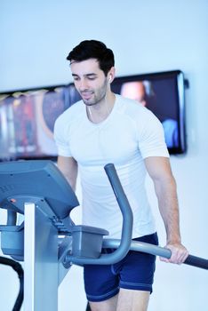 Handsome man running on the treadmill in modern gym