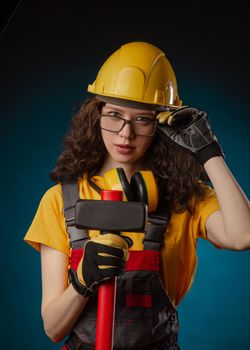 girl in the construction helmet and overalls with a sledgehammer