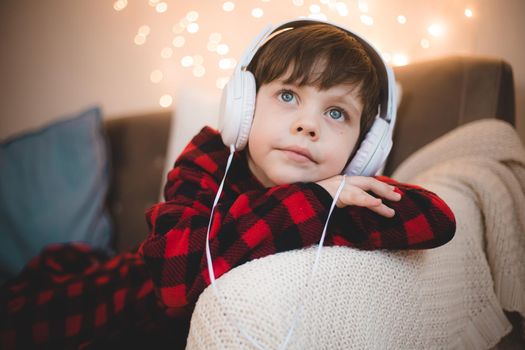 A boy with headphones is lying on the sofa lifestyle. The boy listens to music. New Year's mood.