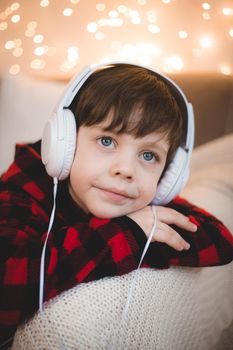 A boy with headphones is lying on the sofa lifestyle. The boy listens to music. New Year's mood.