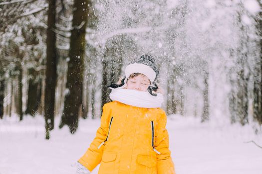 The boy throws snow in winter lifestyle . Winter walks. An article about children's winter leisure. Entertainments