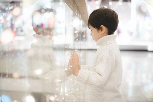 The boy in the winter shopping center does not look at the camera . Holiday shopping. Shopping trip