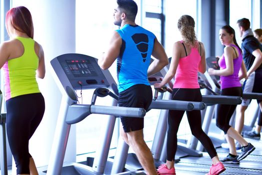 group of young people running on treadmills in modern sport  gym