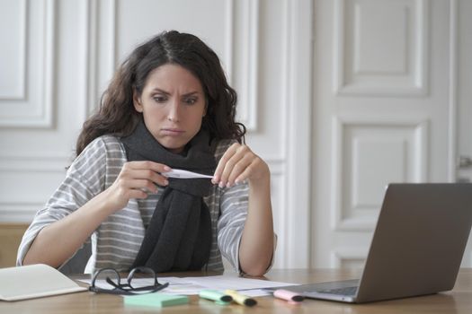 Sad unhealthy italian woman office worker feeling sick, looking at thermometer with worried face expression, measuring temperature at workplace, unhappy female employee with fever at work