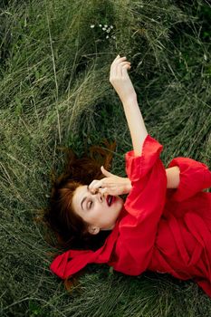 woman in red dress lies on the grass fresh air nature freedom. High quality photo