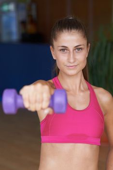 Gorgeou woman girl lifting some weights and working on her biceps in a gym