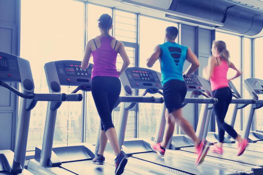 group of young people running on treadmills in modern sport  gym