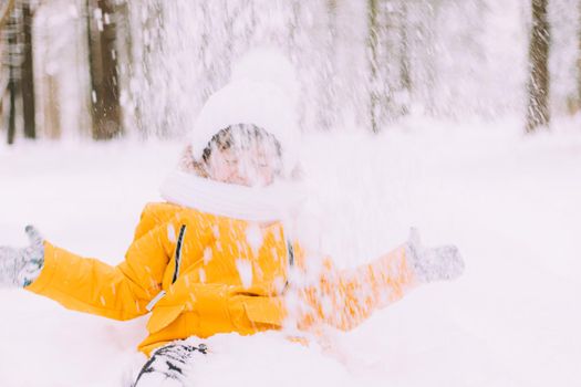 The boy throws snow in winter lifestyle . Winter walks. An article about children's winter leisure. Entertainments