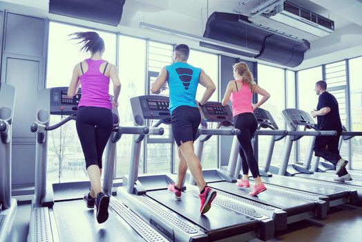 group of young people running on treadmills in modern sport  gym