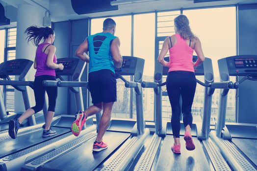 group of young people running on treadmills in modern sport  gym