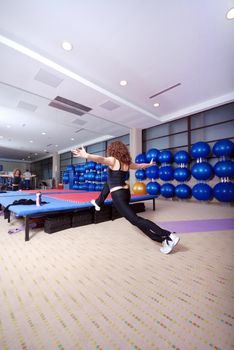 pretty girl warming up andd streching in fitness studio