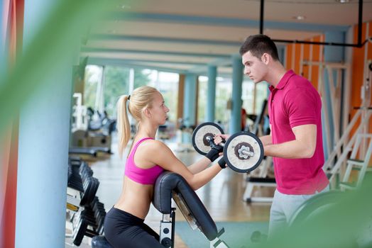 young sporty woman with trainer exercise weights lifting in fitness gym