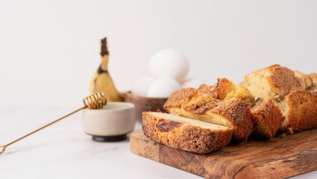 Baking and cooking. Front view of sliced banana bread on light concrete background with honey. Delicious sweet dessert or snack, morning breakfast. Copy space