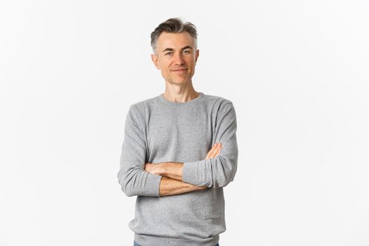 Portrait of attractive middle-aged man standing confident with hands crossed on chest, smiling pleased, posing over white background.