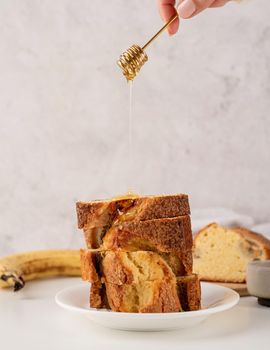 Baking and cooking. Front view of sliced banana bread on light concrete background with honey. Delicious sweet dessert or snack, morning breakfast. Copy space
