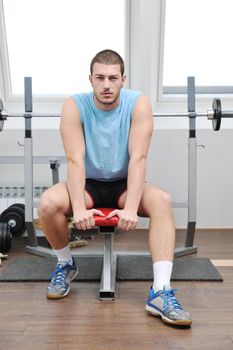 young man in fintess sport club exercise withweights and relaxing