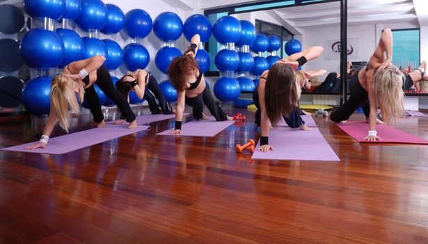 health club: women doing stretching, fitness, aerobics and yoga exercise