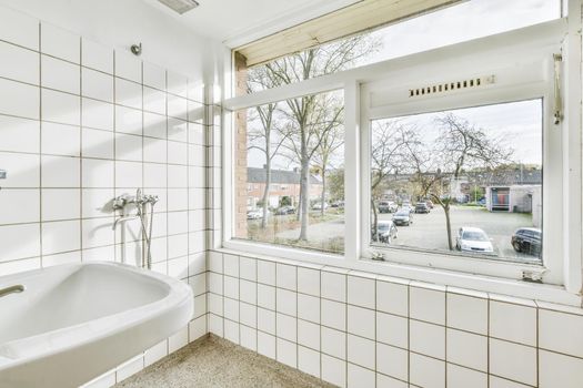 Bathroom with white tiles and a window to the street