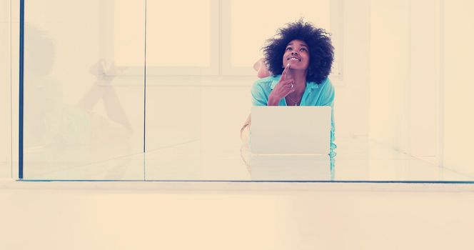 beautiful young african american women using laptop computer on the floor of her luxury home