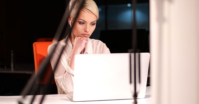 young female entrepreneur working on laptop computer in night office