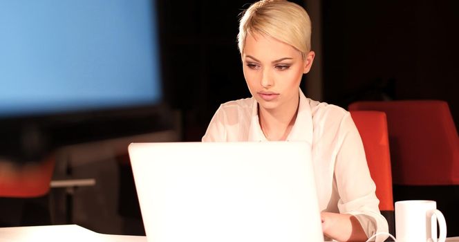 young female entrepreneur working on laptop computer in night office