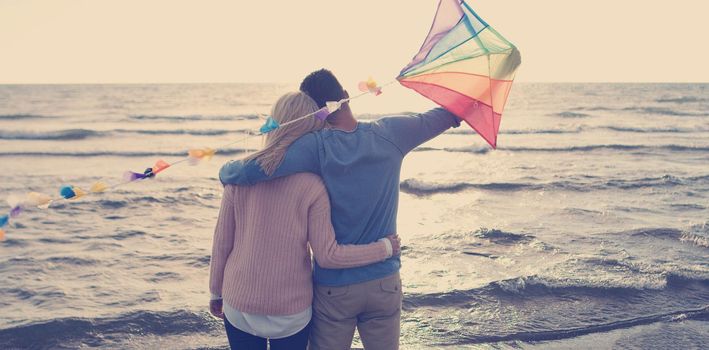 Loving Couple Flying A Kite at Beach and having fun on autumn day