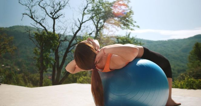 Young Woman Doing Yoga and streching on ball in front of villa