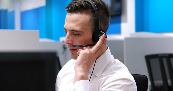young smiling male call centre operator doing his job with a headset