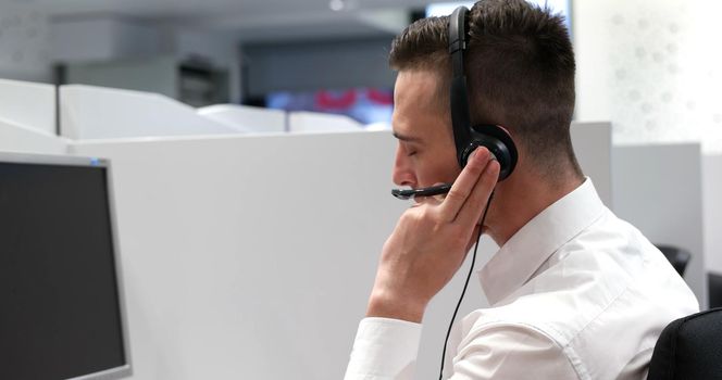 young smiling male call centre operator doing his job with a headset