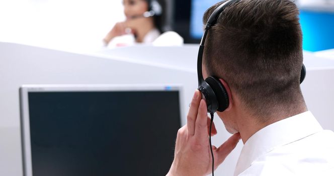 young smiling male call centre operator doing his job with a headset