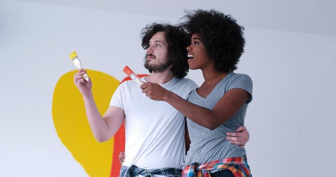 Portrait of loving multiethnict couple with painted heart on wall