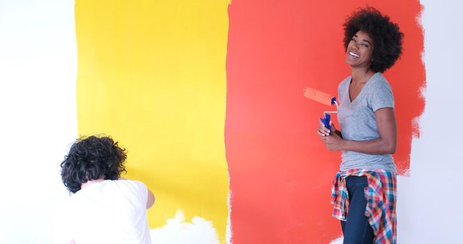 happy young multiethnic couple painting interior wall of new house