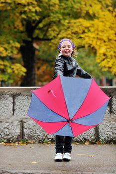 happy girl with umbrella outdoor in park on autumn season rain day