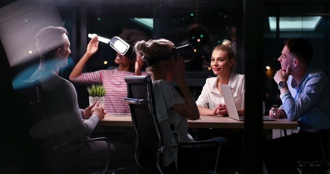 Multiethnic Business team using virtual reality headset in night office meeting  Developers meeting with virtual reality simulator around table in creative office.