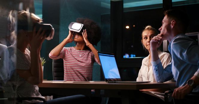 Multiethnic Business team using virtual reality headset in night office meeting  Developers meeting with virtual reality simulator around table in creative office.